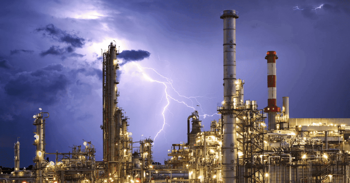 A dramatic image of an industrial factory under a stormy sky, with a lightning bolt striking near the tall structures.