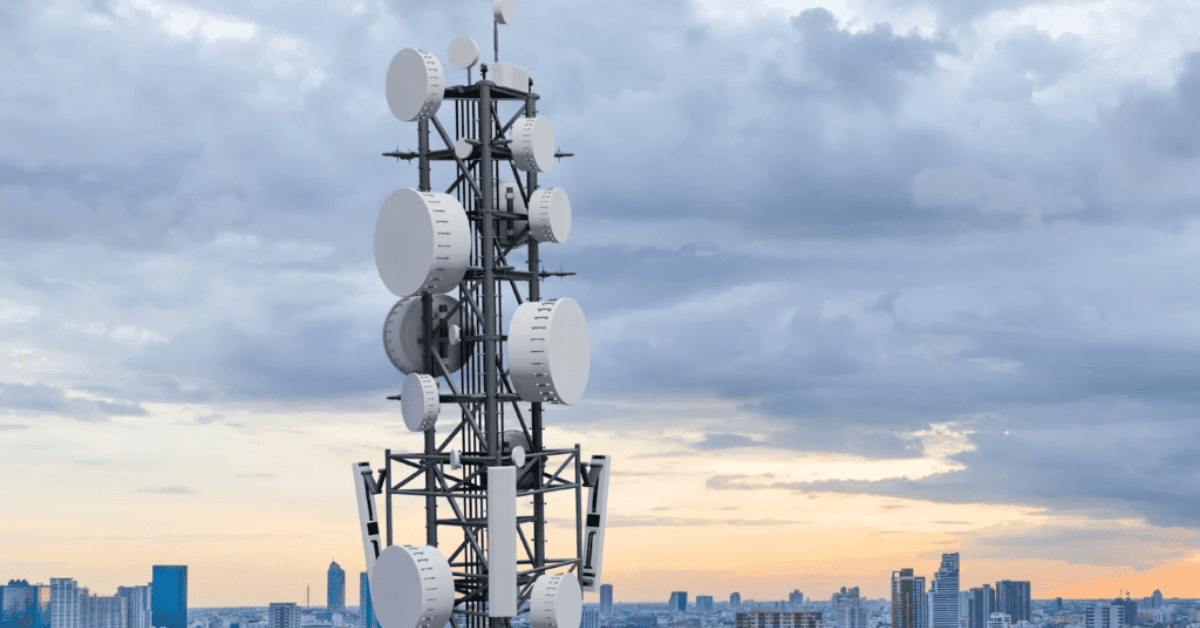 A tall telecommunication tower with multiple antennas against a cloudy sky, equipped with lightning protection systems.